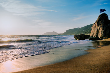 Foamy water  on sandy beach shore at sunset, Agios Gordios beach, Corfu, Greece.