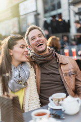 Trendy couple having fun and sitting at a terrace in the city 