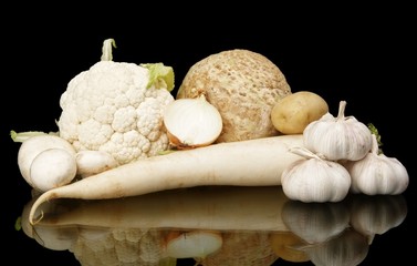 Collection of white vegetables on black with reflection