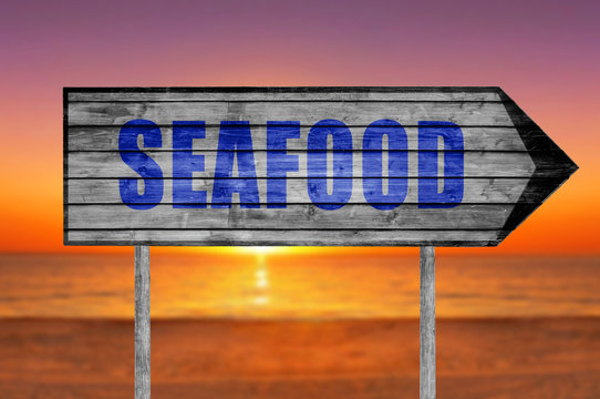 Seafood wooden sign with a beach on background