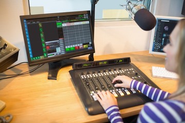 Female radio host in front of screen operating sound mixer