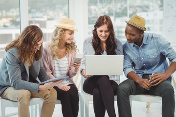 Smiling business people using technology while discussing 