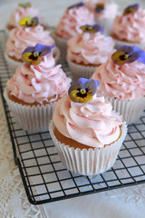Homemade pink frosting vanilla cupcakes with edible flowers