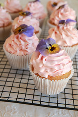 Homemade pink frosting vanilla cupcakes with edible flowers