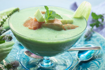 Gurkensuppe mit Minze, Lachswürfel in blauem Glas, auf türkisfarbigem Teller, Dessertlöffel und Lavendelblüten