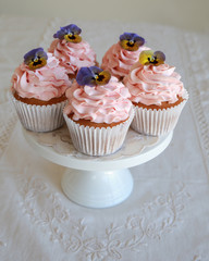 Homemade pink frosting vanilla cupcakes with edible flowers