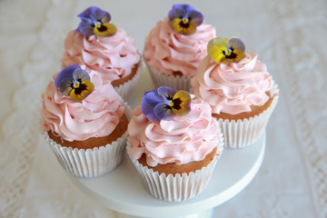 Homemade pink frosting vanilla cupcakes with edible flowers
