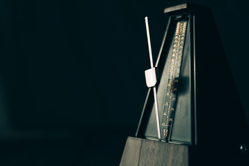 Vintage metronome, on a dark background. - obrazy, fototapety, plakaty