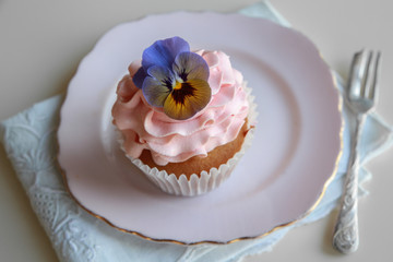 Homemade pink frosting vanilla cupcakes with edible flowers
