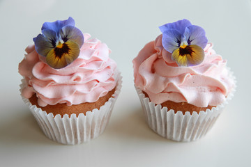 Homemade pink frosting vanilla cupcakes with edible flowers