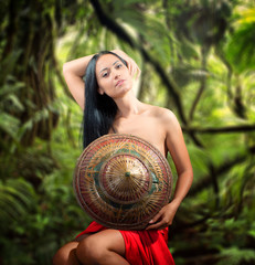 Portrait of a pretty half naked woman with bamboo hat, rainy jungle background
