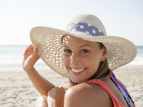 happy girl smiling portrait in the beach  wearing a  hat with the sea and horizon in the background