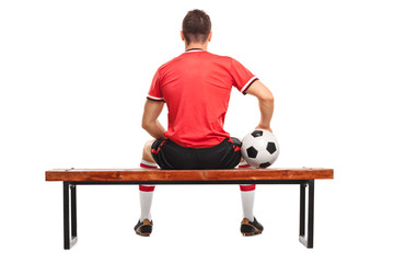 Football player holding a ball and sitting on a bench