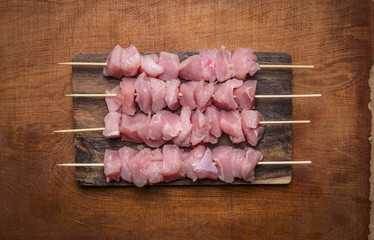 Fresh raw turkey on skewers on a chopping board on wooden rustic background close up top view
