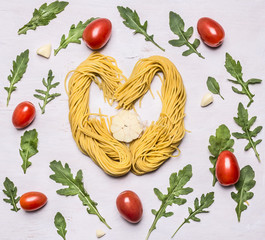 ingredients raw pasta heart lined with cherry tomatoes arugula garlic  on wooden rustic background close up top view