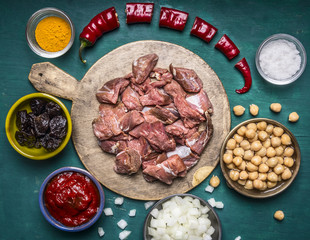 ingredients for cooking lamb canned chickpeas condiment hot red pepper tomato paste prunes sliced onions on a cutting board on wooden rustic background close up top view