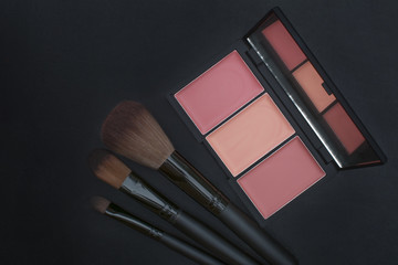 orange tone creamy blusher and makeup brushes on blackboard background