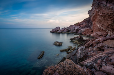 Long exposure shot of Adriatic sea coast and red rock cliff. Sutomore, Montenegro