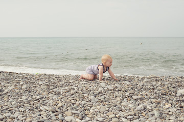 Little girl crawling on the sea beach