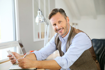 Handsome man sitting in office using smartphone