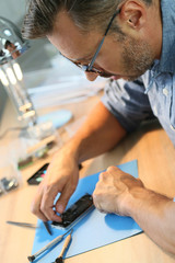 Man repairing broken smartphone in workshop