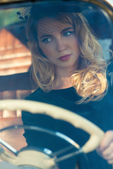 Plakat beautiful fashionable woman at the wheel of a retro car