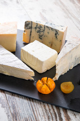 Vassoio nero con fette di formaggi e pezzi di mostarda
