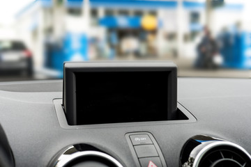 Detailed view of a display at a dashboard in a car. Under the display is the hazards button and on the sides are two car ventilation. Focus is on the black display.