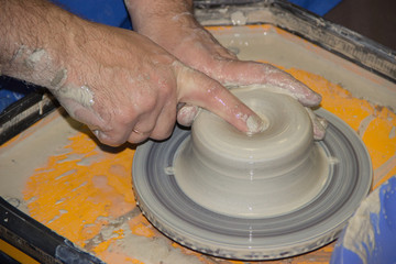 Potter makes on the pottery wheel clay jug. The hands of a potte