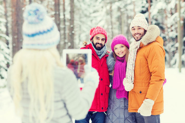 Fototapeta premium smiling friends with tablet pc in winter forest