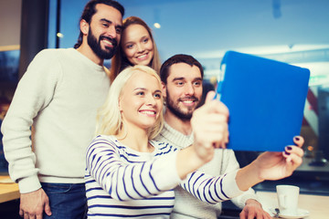 happy friends with tablet pc taking selfie at cafe