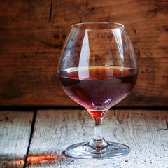 Cognac in a glass on the old wooden background, selective focus