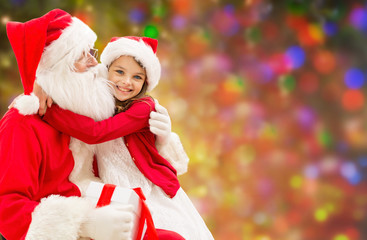 smiling girl cuddling with santa claus over lights