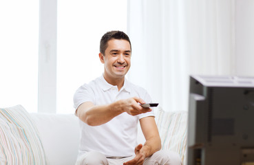 smiling man with remote control watching tv