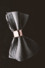 Grey napkin in the vintage metal ring on the black wooden table