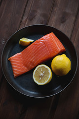 Above view of a frying pan with salted trout fillet and lemon