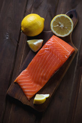 Salted trout filet with lemon on a dark rustic wooden background
