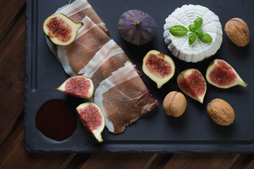Basalt plate with ricotta, figs, ham and walnuts, above view