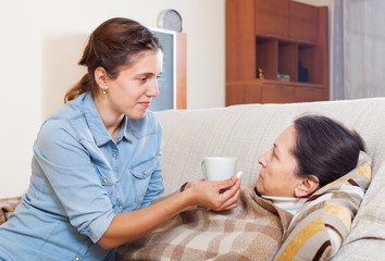 Fototapeta premium daughter giving pills to sick mature woman