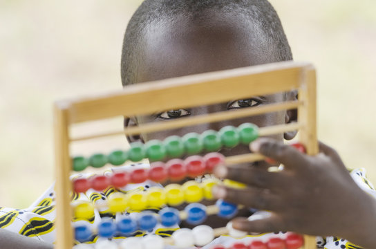 Handsome Young African Black Boy Playing with an Abacus School. Back to School symbol: young black boy playing with an abacus toy at school. handsome little man learning to count using a known game.