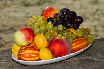 Fruits on a plate on a big old tree stump in the garden