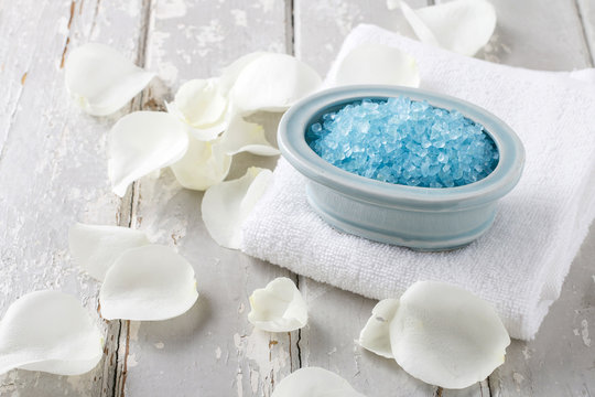 Bowl of blue sea salt, white rose petals around