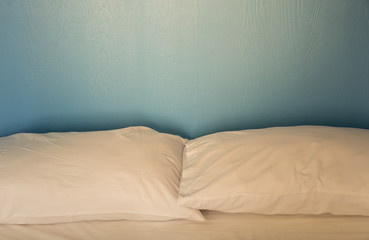 An unmade bed with white linens background blue wood