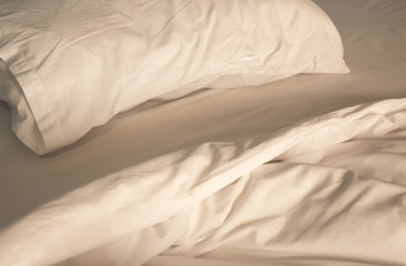 An unmade bed with white linens