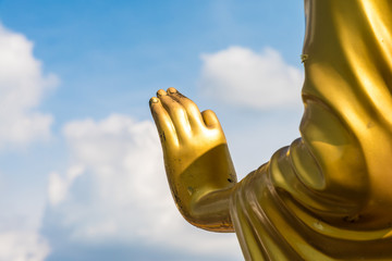 Golden buddha hand on 'O.K.' sign (peace) with blue sky and clou