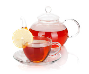 Glass teapot and cup of black tea with lemon slice