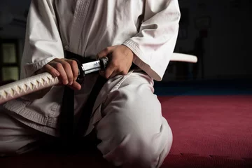Abwaschbare Fototapete Kampfkunst Nahaufnahme eines jungen Kampfkunstkämpfers mit Katana-Standort in Seiza-Position
