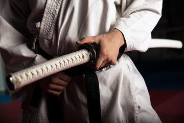 Close up van jonge vechtsportvechter met katana aanbrengen in seiza-positie