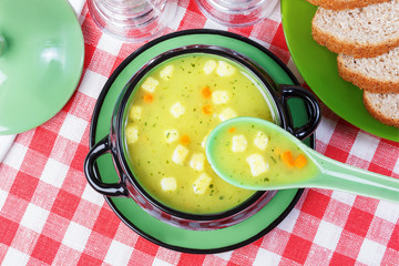Soup with croutons in a tureen, bread on a plate, napkin, spoon