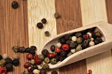 Grains of colored pepper on a wooden plank.